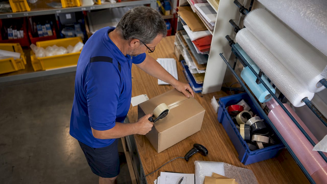 Postal worker taping international parcel