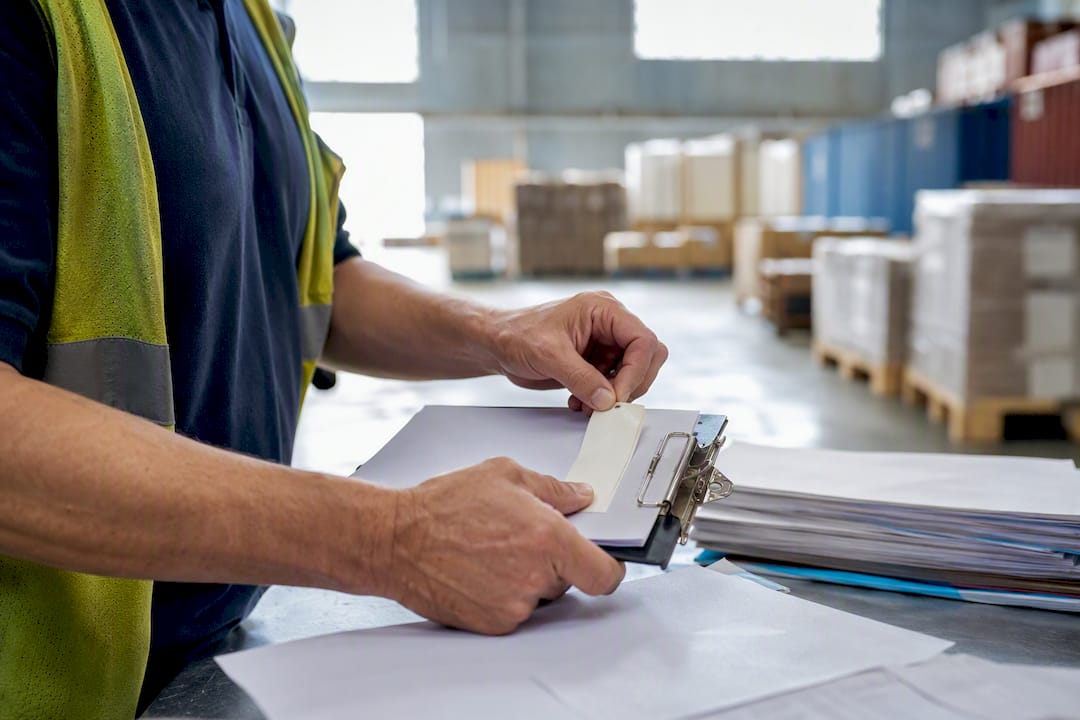 Hands placing container number sticker on clipboard