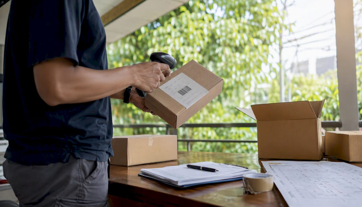 Hands scanning DHL parcel shipping label barcode