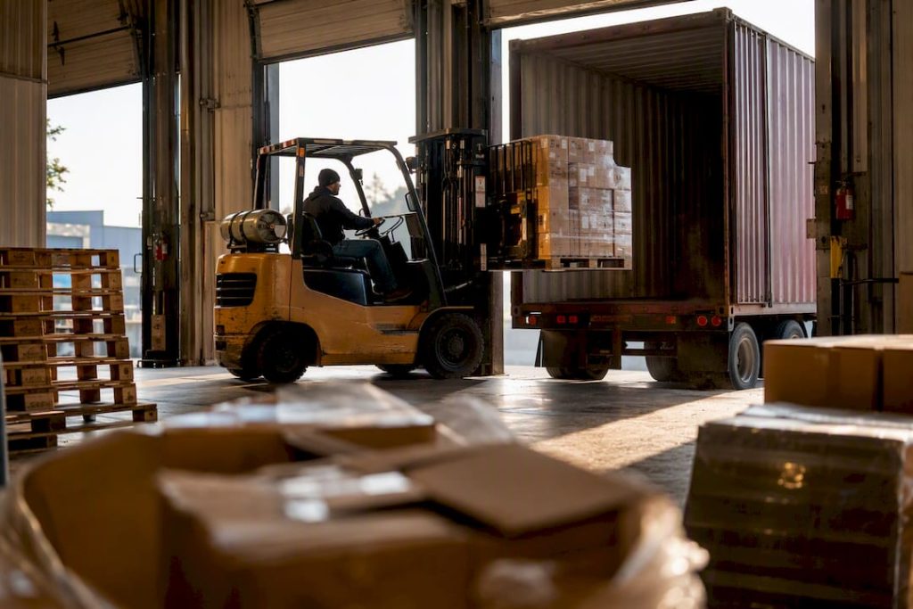 Forklift loading freight pallets at warehouse dock