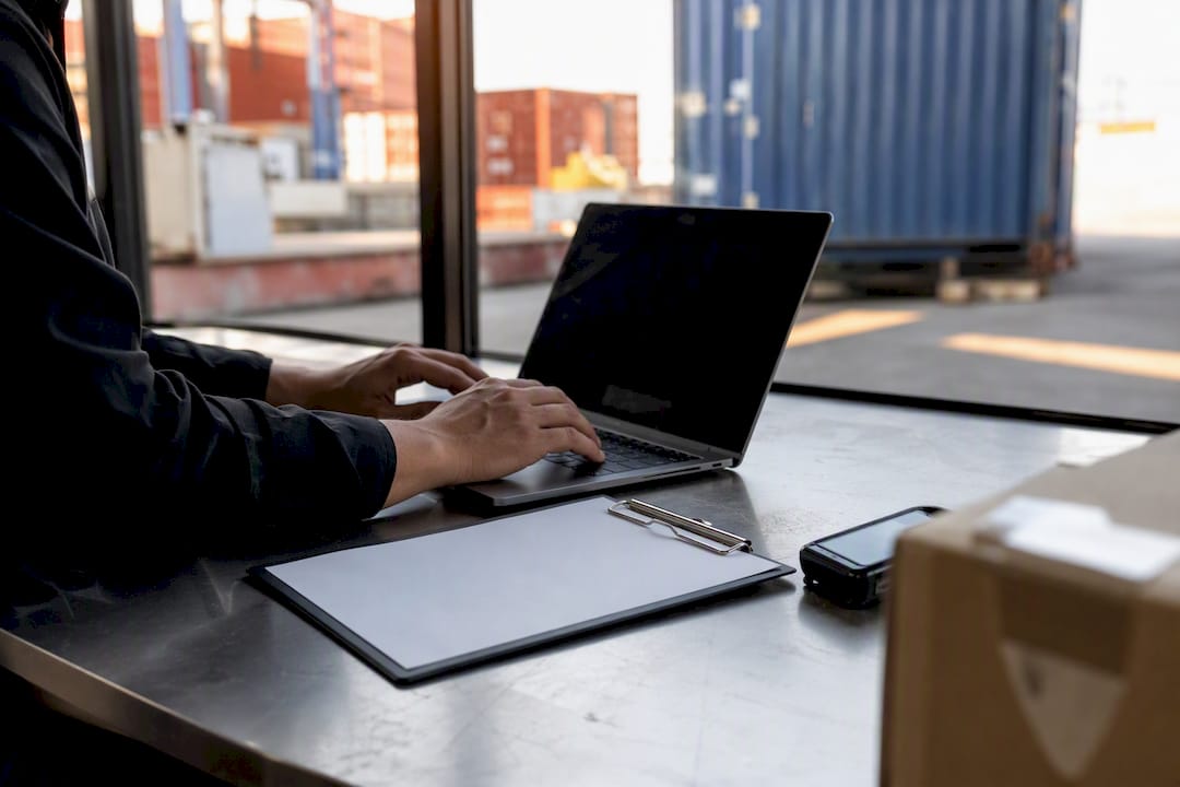 Hands entering import declaration data on laptop