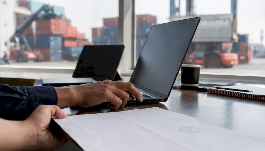 Hands entering shipping bill data at customs counter