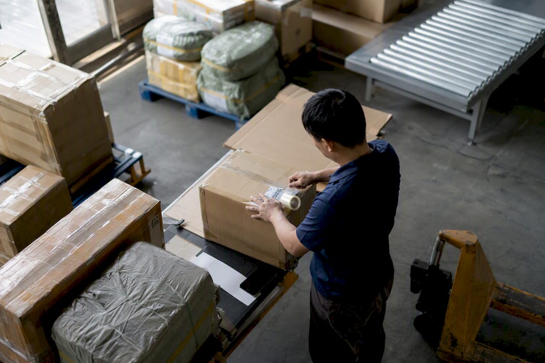 Hands labeling shipping packages in freight facility